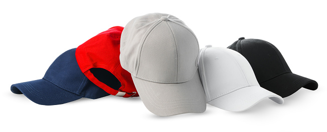 A collection of baseball caps in various colors neatly arranged next to a single baseball, all set against a clean white backdrop