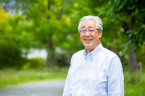 Portrait of an elegant middle-aged Japanese man, taken outdoors in fresh greenery