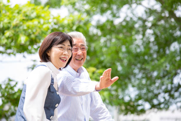 istock A middle-aged Japanese couple smiling and talking on a park bench 2095712184