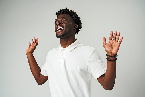 Young African Man Standing With Hands Raised in studio