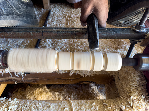 Turner working on a lathe in the workshop curving woods