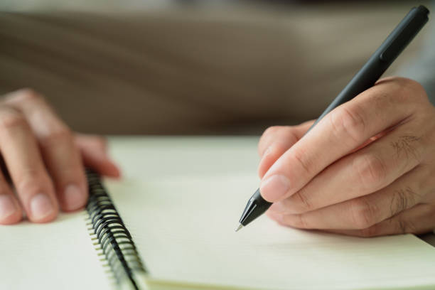 istock A man is writing in a notebook with a black pen 2095769112