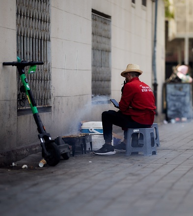 Istanbul, Turkey – April 23, 2023: Person in hat sits on stool outdoors