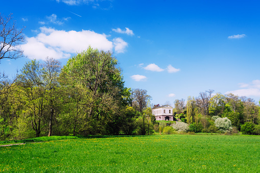 Weimar, Germany - May 3, 2023: A vibrant springtime landscape showcasing lush green fields and a quaint house amidst flourishing trees in Weimar, Germany.