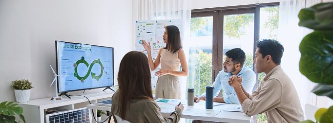 Asian woman lead young group of multiethnic businesspeople in team meeting, using laptop computer for ESG topic presentation on monitor. Sustainable business practice, people work at home concept