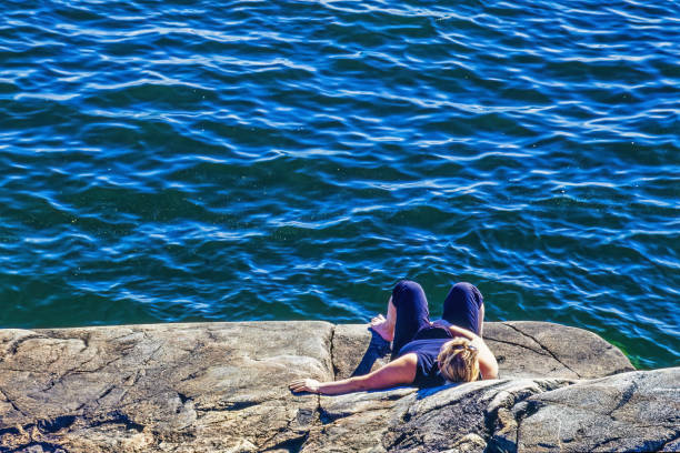 Sunbathing woman on a cliff by the sea
