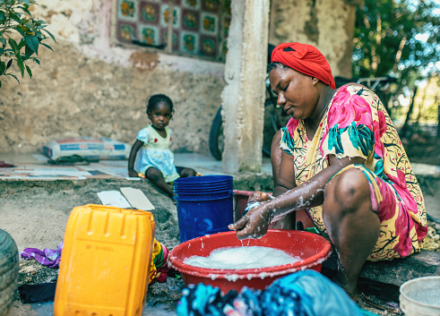 A young African mother washes her laundry outside