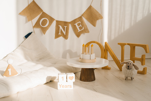 Photo zone for shooting a one-year-old baby's birthday in pastel colors. Mattress, wooden toys and cake