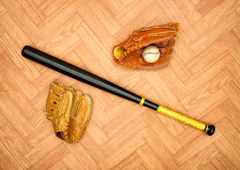 Baseball gloves and bat on the parquet