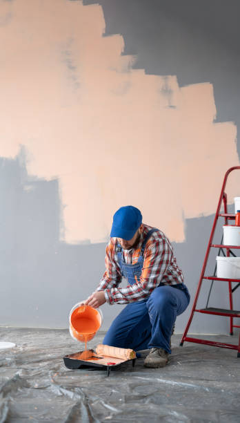 istock House painter pouring orange wall paint into tray, preparing for renovation and remodeling apartment 2095851295
