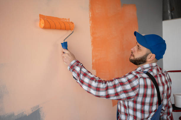 istock Bearded man painter painting a wall orange with a paint roller. Place for text 2095851296