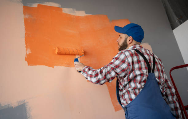istock Painter painting a wall with roller and orange paint. New home renovation concept 2095851302