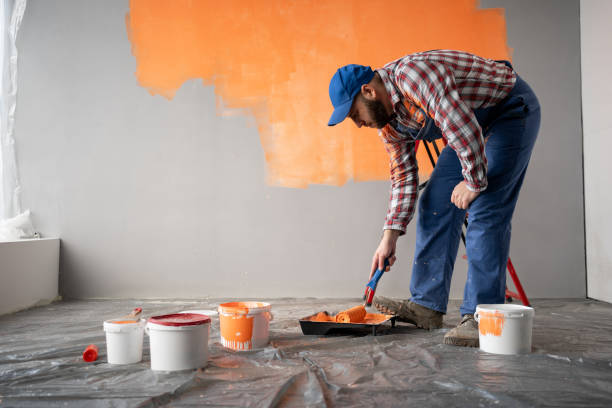 istock Concentrated handyman in overalls is preparing paint roller for work 2095851303