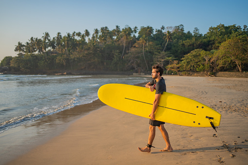 Young man heads out to sea with surfboard