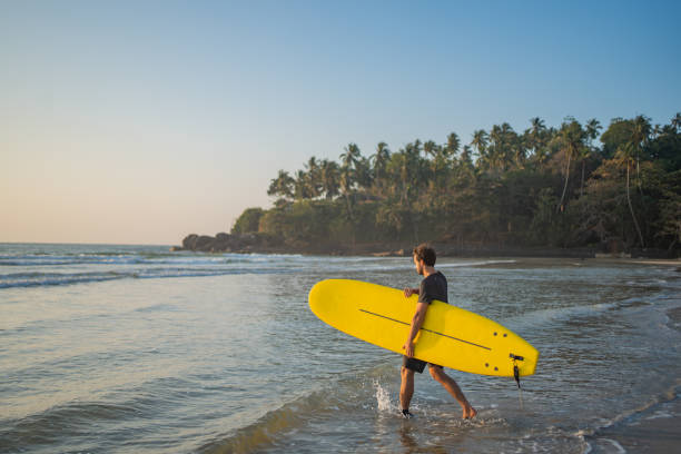 istock Young man heads out to sea with surfboard 2095869439