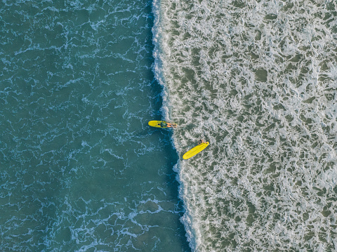 Aerial view of young women surfing on rolling waves