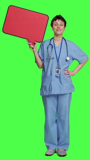 Front view Medical assistant holding a red speech bubble icon against greenscreen