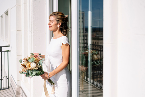 Beautiful blonde-haired woman in a white dress on the balcony of a hotel in Madrid, Spain. On your wedding day before you get married.
