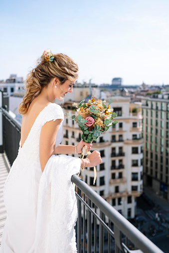 Beautiful blonde-haired woman in a white dress on the balcony of a hotel in Madrid, Spain. On your wedding day before you get married.