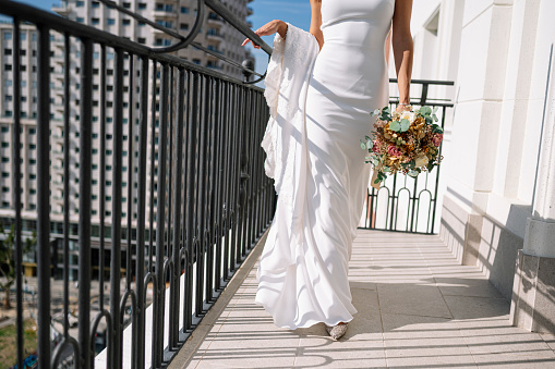Beautiful blonde woman in a white dress walking on the balcony of a hotel in Madrid, Spain. On your wedding day before you get married.