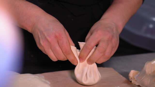 Close-up of female chef's hands sculpting khinkali. Process of making khinkali