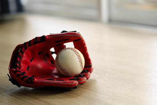 Baseball ball in a glove on the wooden table with copy space. Sport concept.