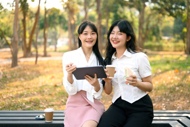 istock Two cheerful office workers using digital tablet and chatting on a coffee break at outdoor 2095931837