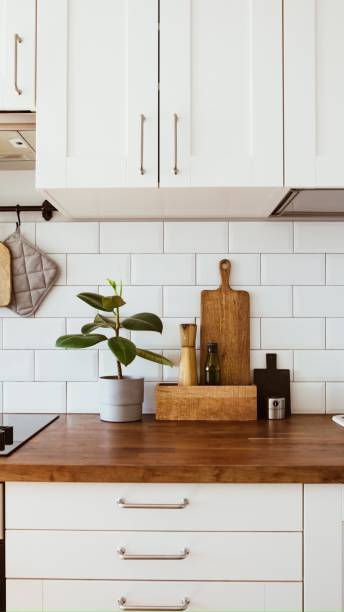 istock Kitchen brass utensils, chef accessories. Hanging kitchen with white tiles wall and wood tabletop.Green plant on kitchen background 2095933454