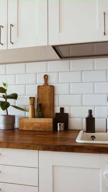 istock Kitchen brass utensils, chef accessories. Hanging kitchen with white tiles wall and wood tabletop.Green plant on kitchen background 2095933947