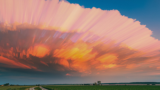 Of Moving Clouds Trails Sky. Amazing Effects Of Smeared Clouds. Long Exposure Fasters Clouds Above Countryside Rural Field Landscape. Sunlight Shining Through Clouds. Sunrays, Sunray, Ray, Dramatic Sky. Magenta Clouds. Pink And Blue Union.