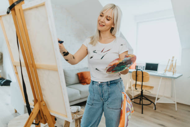 istock Creative young woman painting on canvas at home 2095953533