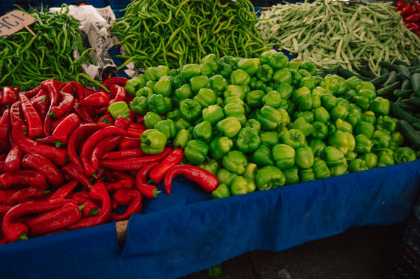 A pile of green peppers and red peppers are displayed in a wooden crate. The contrast between the two colors creates a visually appealing display