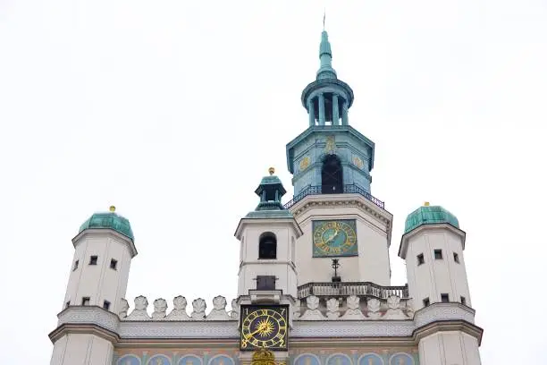 A photo of the old market square in Pozna, Poland, taken in January during winter. Snow-covered rooftops with the historic town hall against a white sky backdrop.