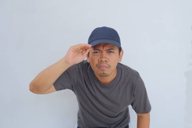 istock Perplexed man in cap and t-shirt saluting against a white background 2096044738