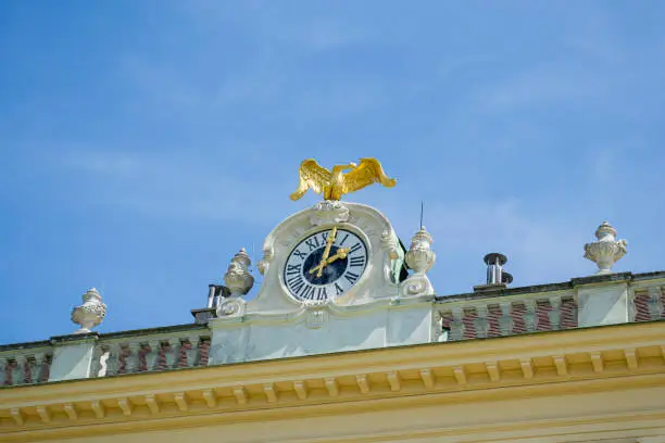 Ornamental golden clock on a building, Vienna, Austria against the blue sky.