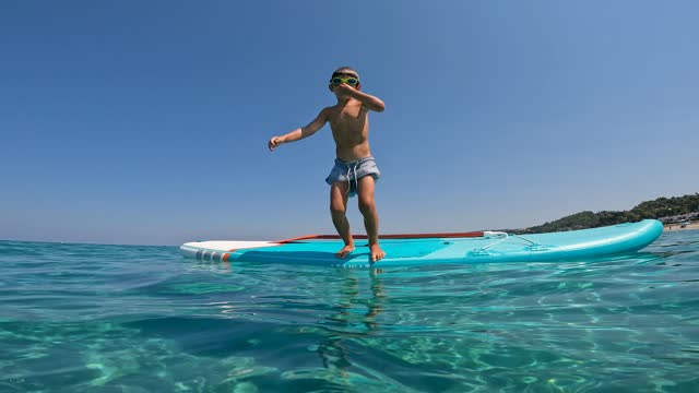 Boy jumping into the sea off the paddleboard