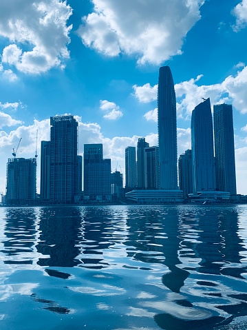 Skyscrapers reflected in the blue river at Dubai Creek