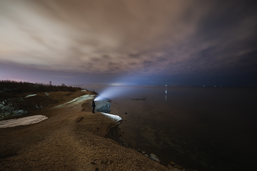 Night photo, a man with a headlamp on the sea cliff of Paldiski. High quality photo