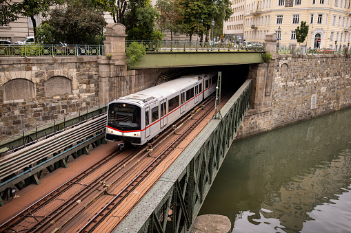 Subway train moving on the railway bridge over the river in Vienna, Austria.