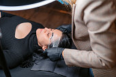 Female Beautician Putting A Plastic Cover After Microblading Her Client's Eyebrows At A Beauty Salon