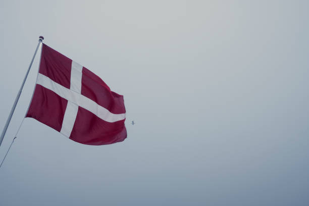 Close-up of Denmark national flag waving on a clear day. Red flag with a white Scandinavian cross extending to the edge of the flag. 3d illustration render. Fluttering fabric. Selective focus