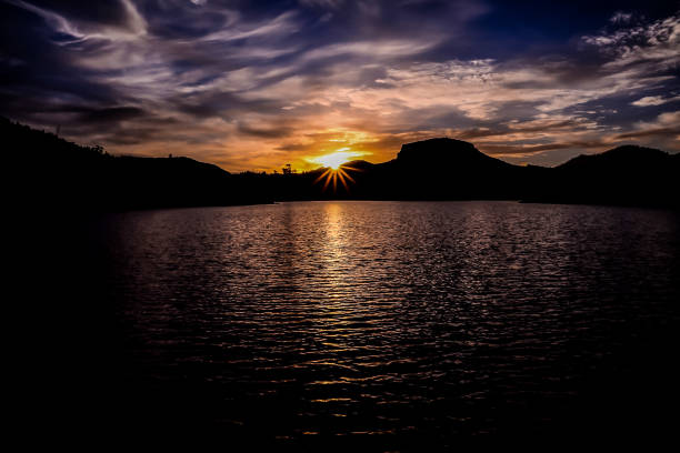 sun behind a mountain silhouette - image alternative energy canary islands color image - fotografias e filmes do acervo