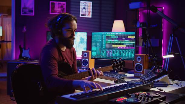 istock Musical composer recording his guitar tunes and adding piano key sounds 2096126787
