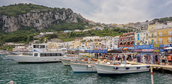 Panoramic view of Capri island harbor with tourist boats arriving from mainland Italy.