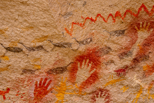 Close up of colourful animal rockpaintings of llamas and handprints on rockwalls at Cueva de las Manos, UNESCO World Heritage Site, Patagonia, Argentina