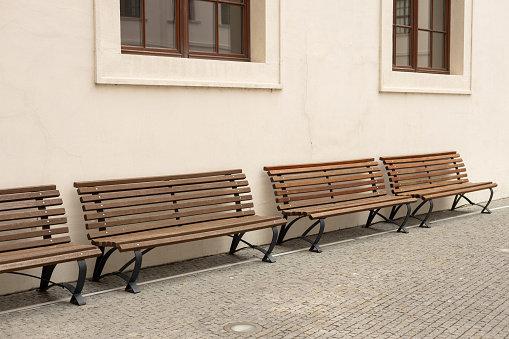 Four bench seats against beige wall. Bench in front of a stone wall