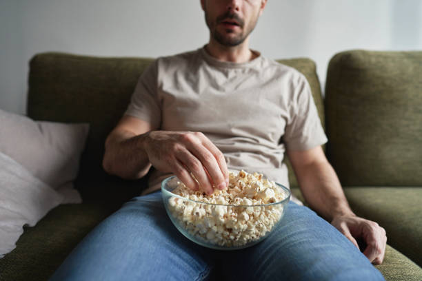istock Man eating popcorn and watching TV 2096168238