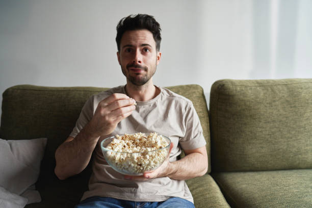 istock Man eating popcorn and watching TV 2096168765