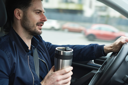 Man using reusable mug in the car