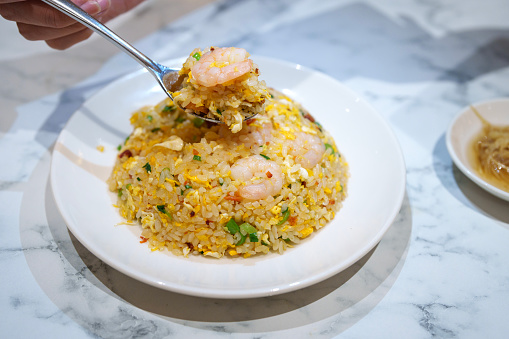 High angle view a woman is seen enjoying shrimp and egg fried rice at a Chinese restaurant